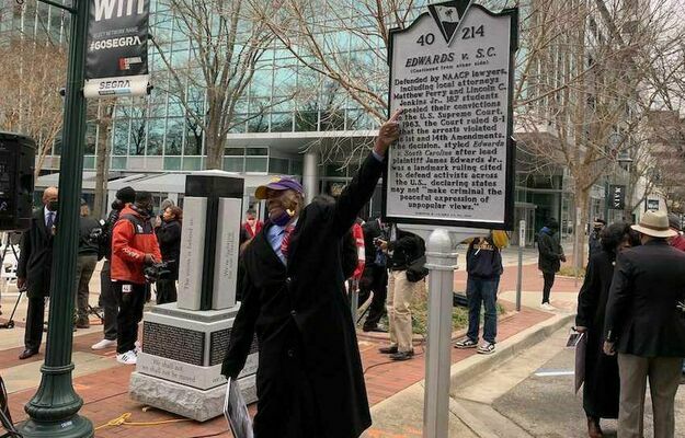Rev. James Edwards touches a monument to protesters in the 1961 march on the State House.